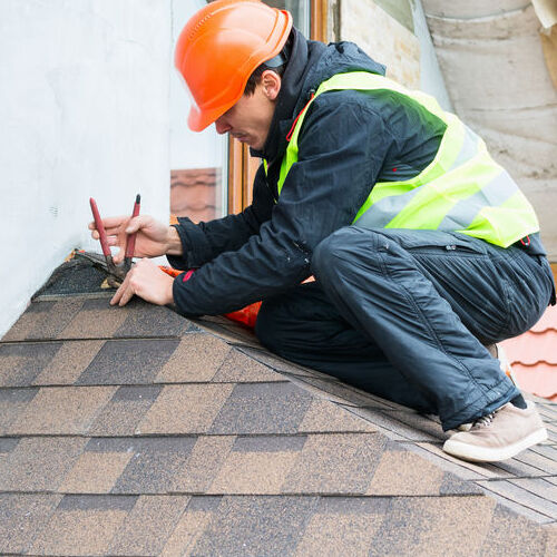 A Roofer Removes Damaged Shingles.