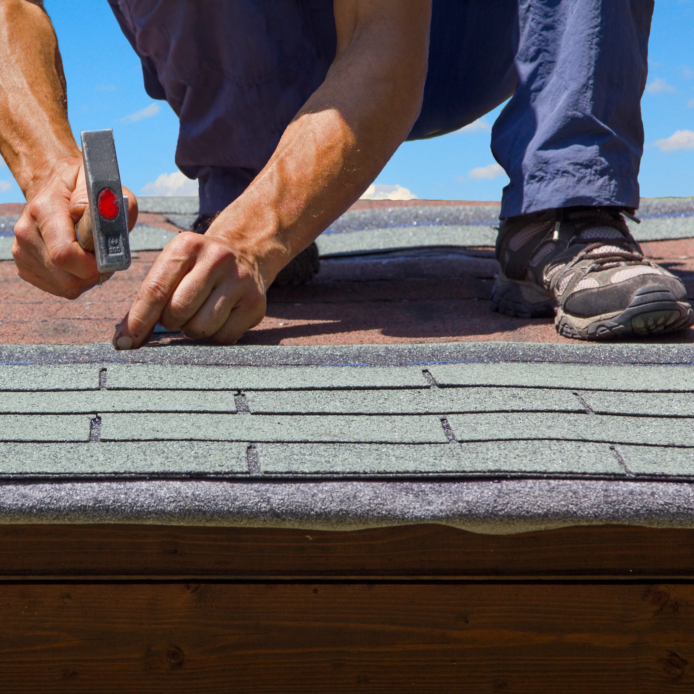 A Roofer Nails in Shingles